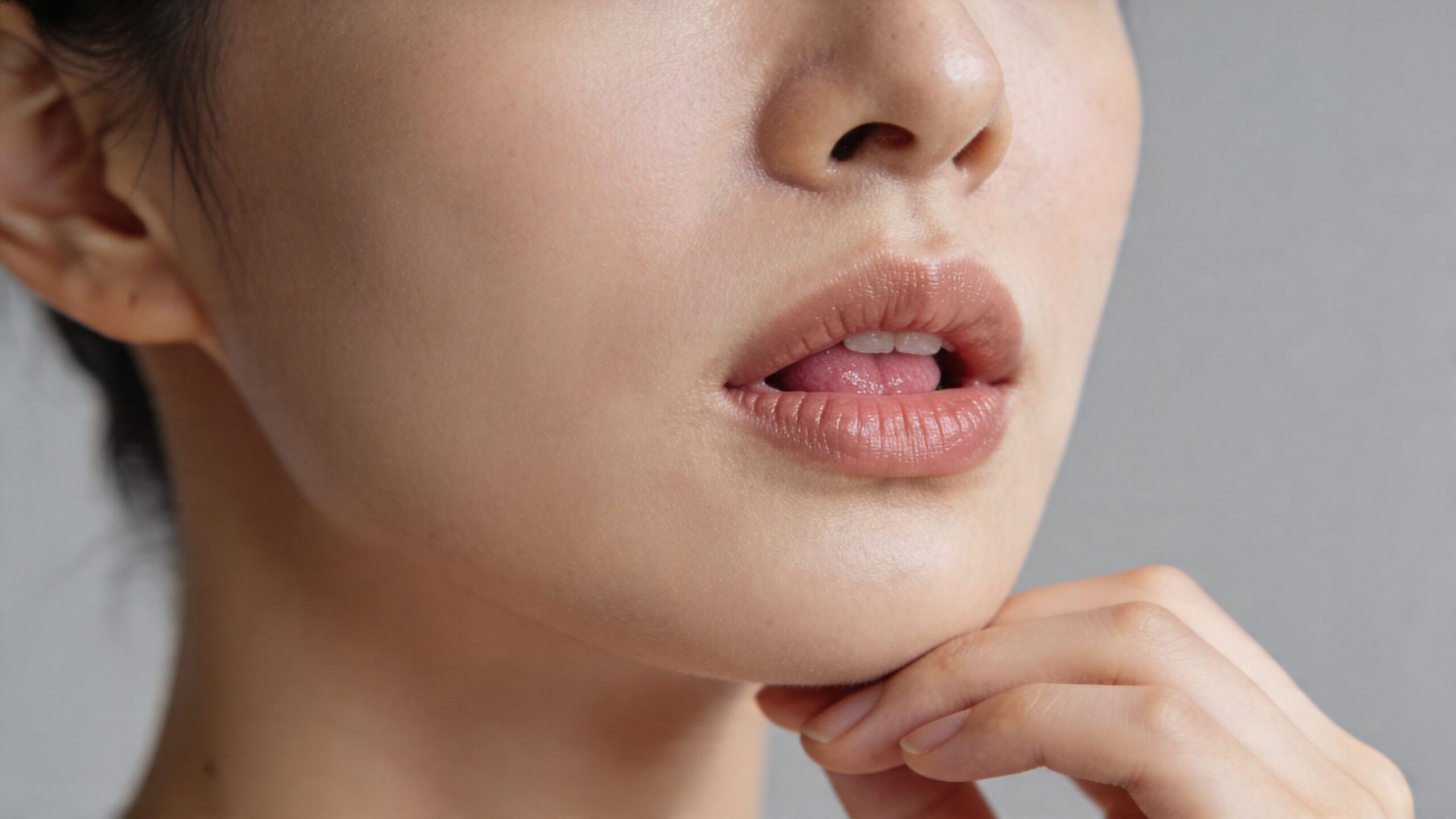 A close-up view of a person's mouth and chin area, emphasizing clear, healthy skin and lips.