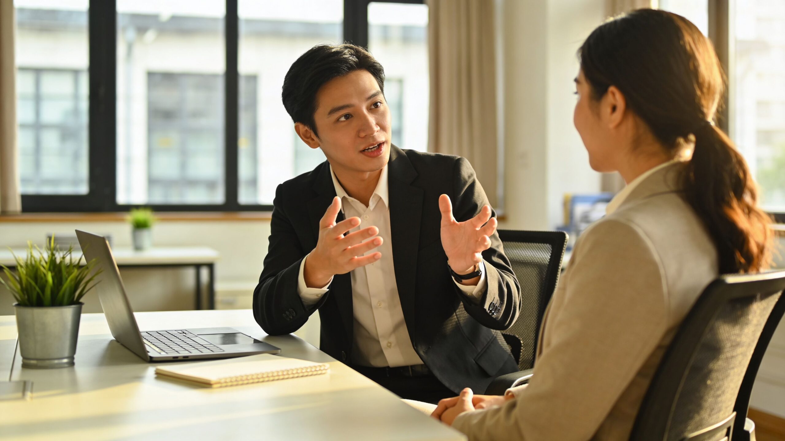 A professional man and woman having a productive business discussion in a brightly lit modern office.