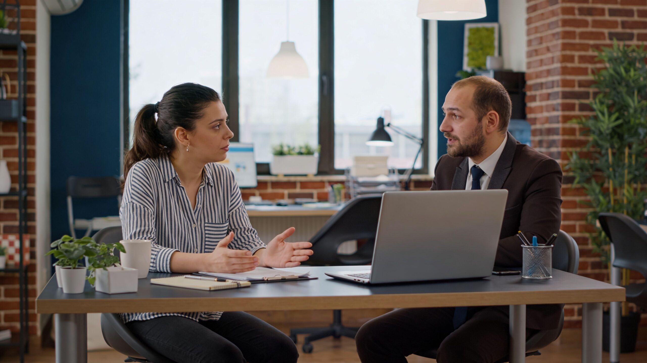 A businesswoman and a professional male consultant having a collaborative discussion at a modern office desk.